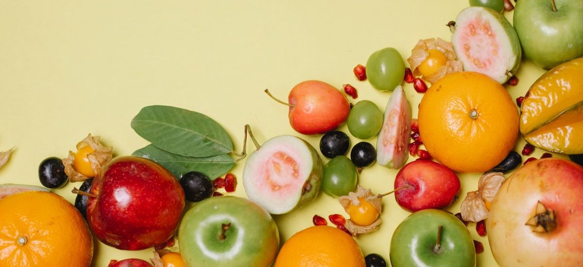 Top view of different fresh appetizing healthy fruits and berries on beige background