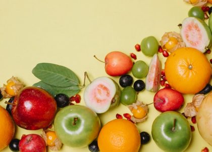 Top view of different fresh appetizing healthy fruits and berries on beige background