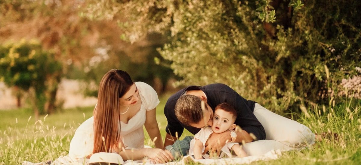 A happy family having a picnic in a lush green park setting during the day.