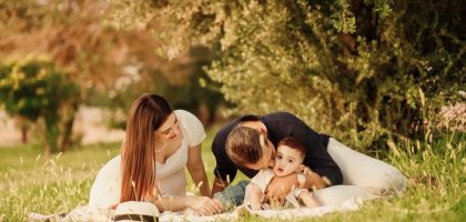 A happy family having a picnic in a lush green park setting during the day.